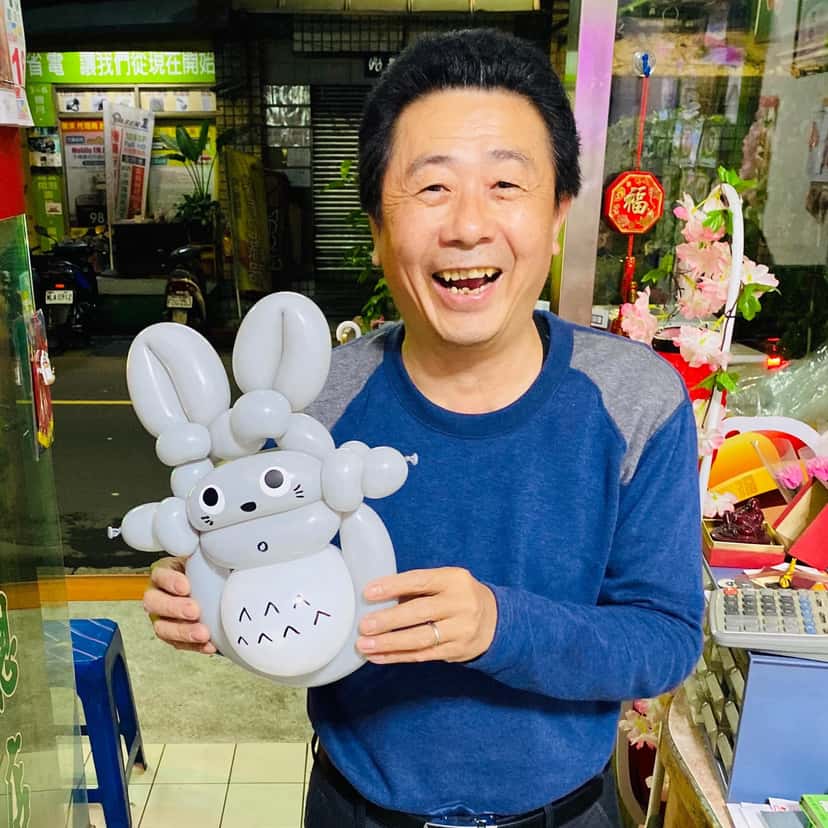 柯爹開心大笑，雙手抱著自己看教學影片完成的灰色龍貓氣球