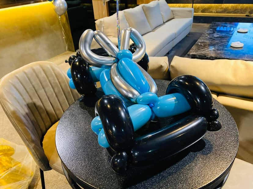 高腳桌上的藍銀黑三色賽車造型氣球，車頭繫著銀色蝴蝶結