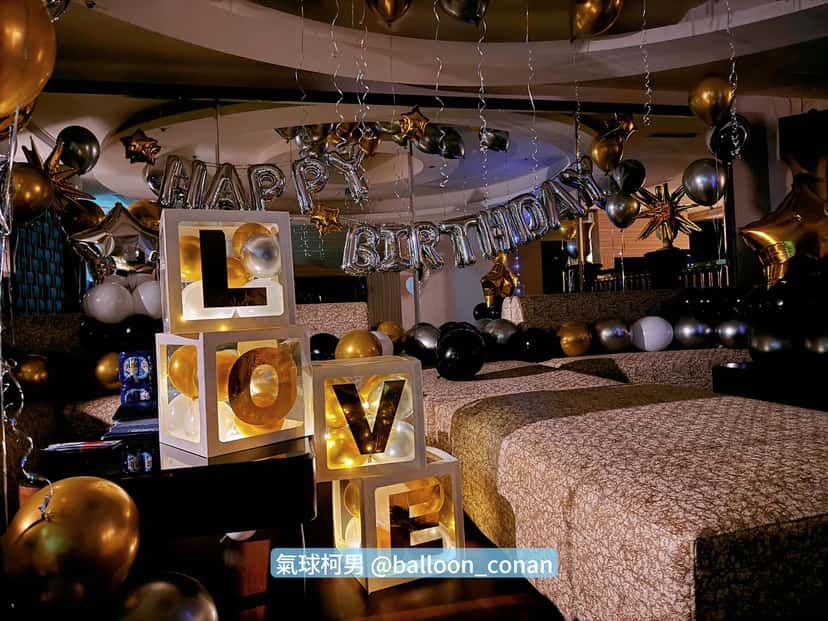 關燈後 LOVE 字母燈箱透出暖黃光，後方掛著銀色 HAPPY BIRTHDAY 字母氣球