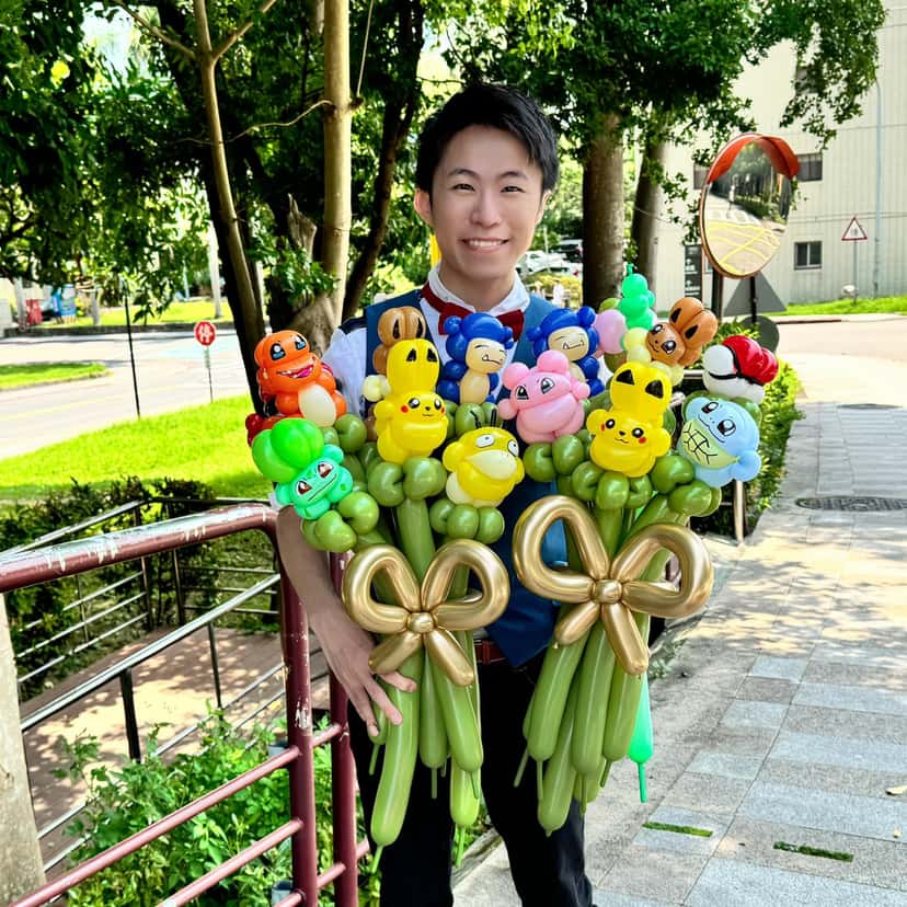 柯男在戶外雙手抱著兩束寶可夢氣球花束，綁著金色蝴蝶結