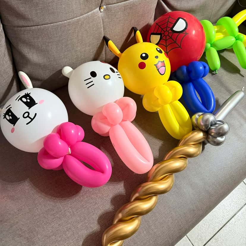 灰色沙發上排著兔兔、Hello Kitty、皮卡丘、蜘蛛人手持氣球，前方一支金色扭紋與銀色的獨角獸角氣球，右上角有綠色氣球