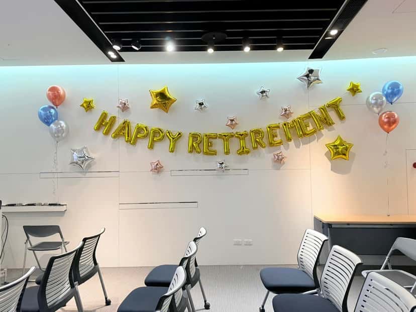 會議室白牆的金色 HAPPY RETIREMENT 字母氣球與金銀星星鋁箔