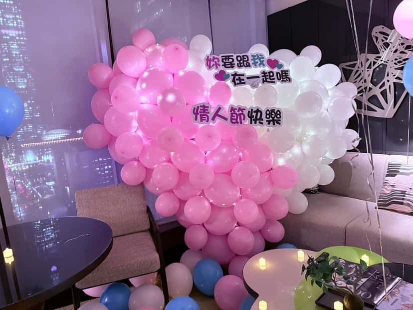 粉紅與白色氣球組成的大愛心，掛著「妳要跟我在一起嗎」與「情人節快樂」字牌