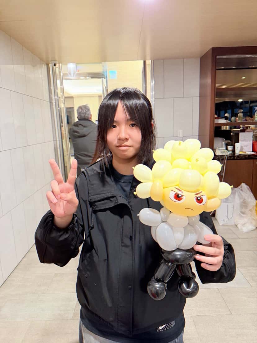 12 月抓周：黑色外套女生比 YA，手拿爆豪造型氣球
