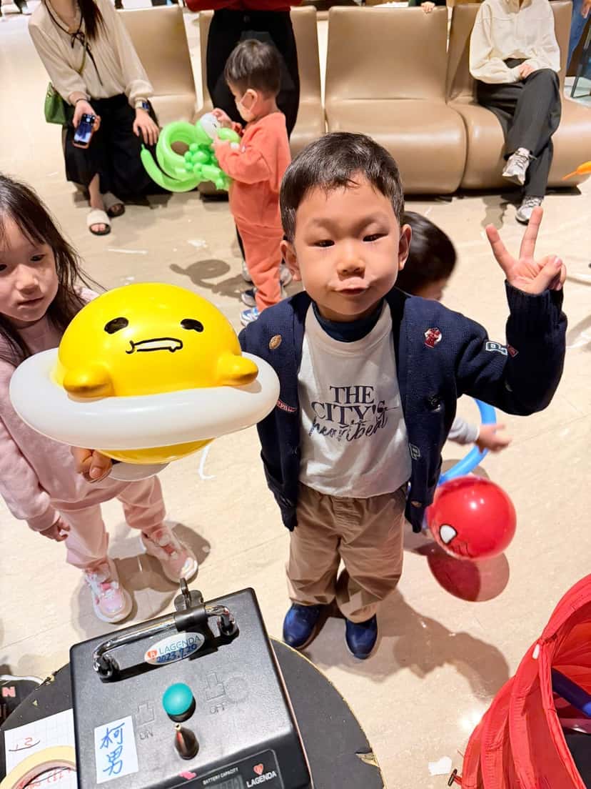 1 月生日派對：小男孩比 YA，女孩拿著黃色蛋黃造型氣球