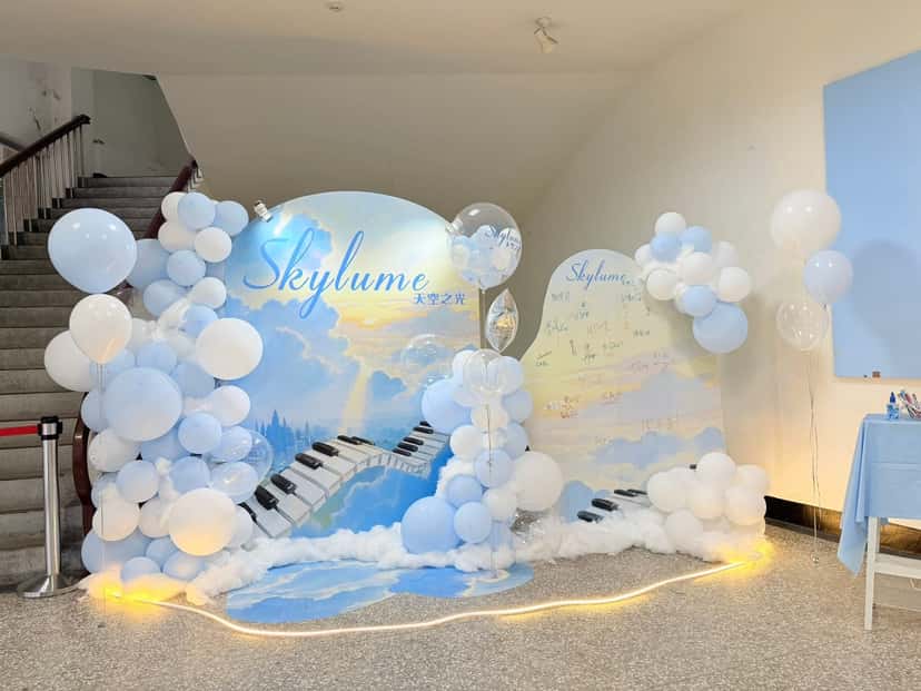 天空與琴鍵插畫的雙片拍照背板，周圍堆疊淺藍、白色與透明氣球，底部鋪滿棉花雲朵