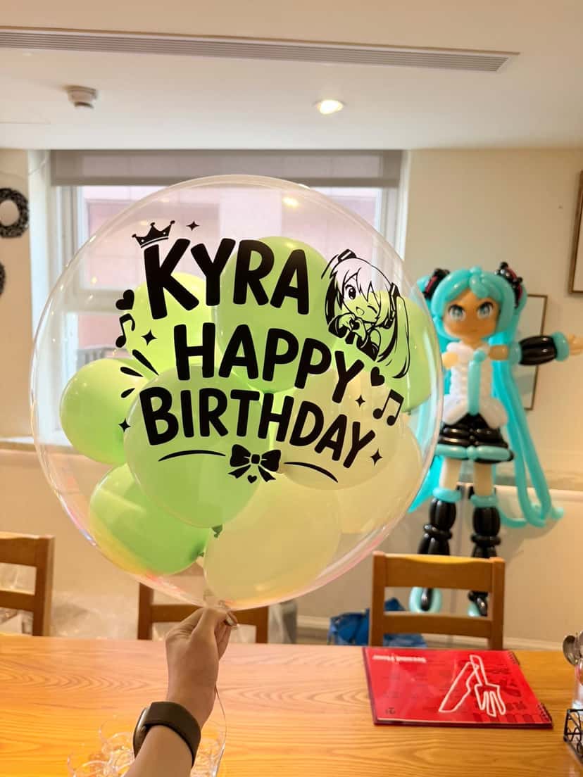 初音未來中型氣球人偶站在金銀色底座，藍綠雙馬尾、黑白服裝