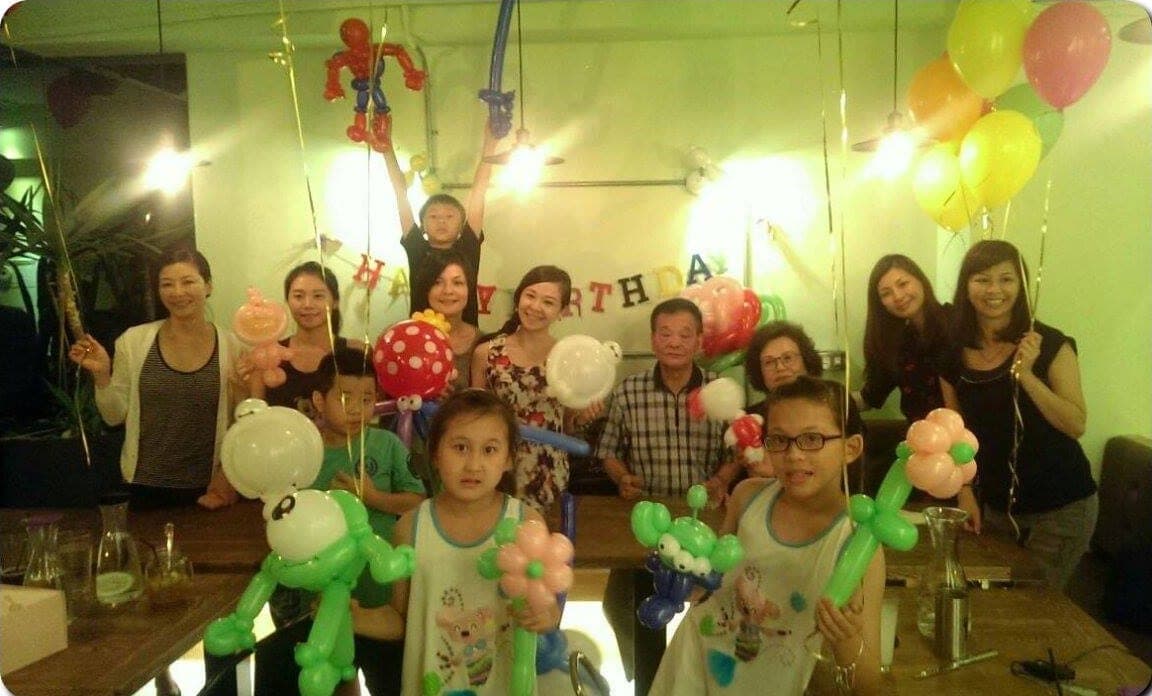 咖啡廳生日派對大合照，大人小孩拿著各式造型氣球