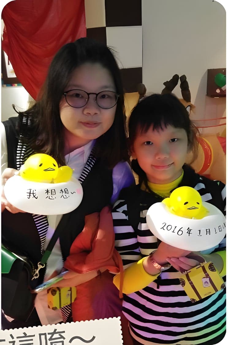 兩個女孩拿著寫字的蛋黃哥造型氣球，蛋白上寫著 2016 年 1 月 1 日