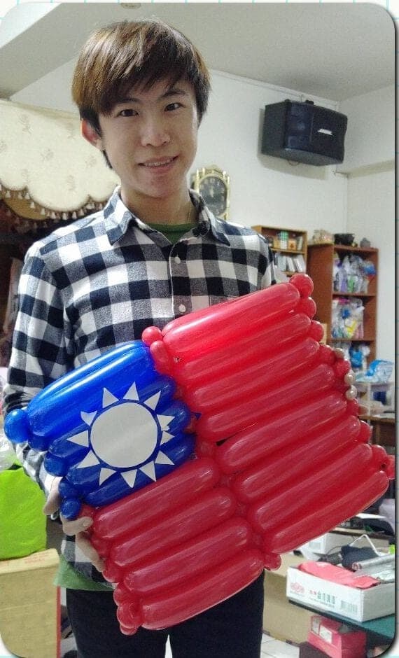 我拿著用長條氣球排成的青天白日滿地紅國旗造型氣球