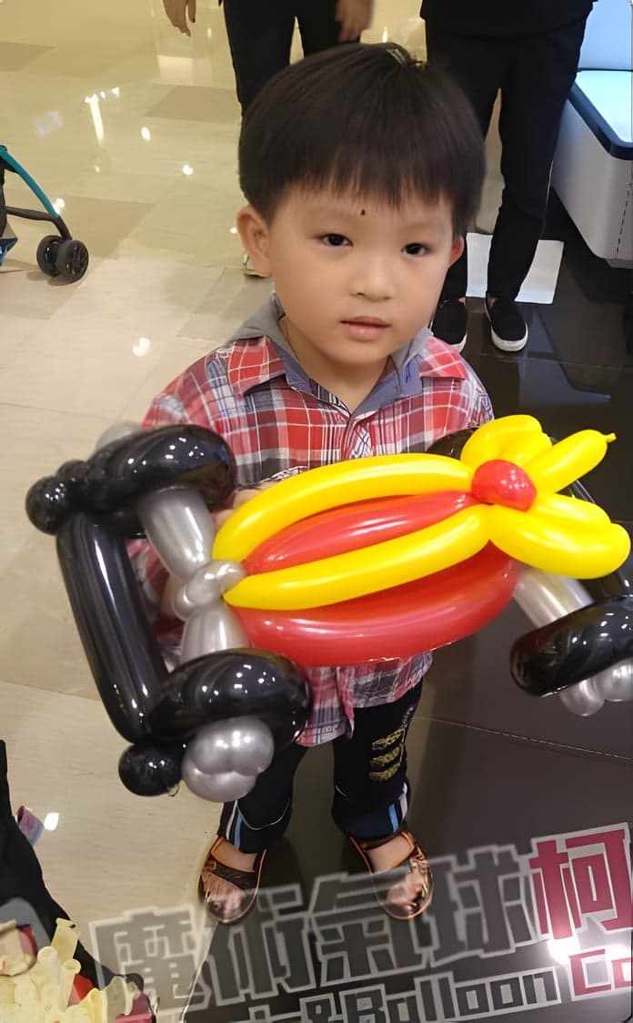 男孩拿著紅黃色賽車造型氣球