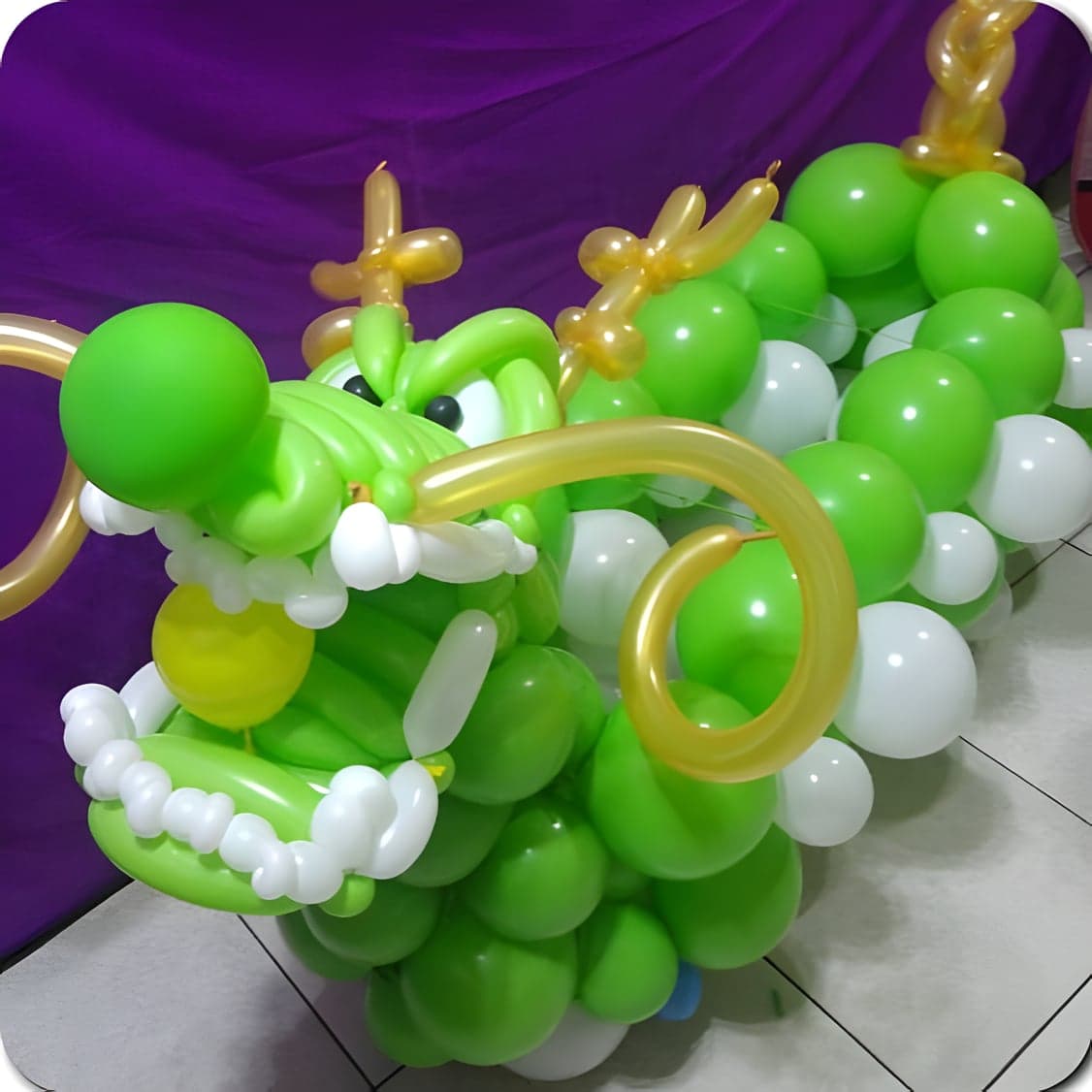 綠色氣球龍舟的龍頭近照，金色龍角與白色牙齒