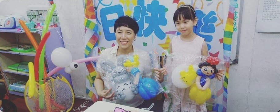 戴皇冠的小壽星和媽媽捧著用透明袋包好的造型氣球