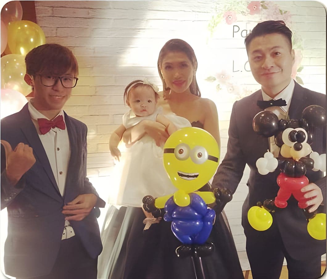 婚禮喜宴上，新娘抱著寶寶和新郎拿著小小兵、米奇造型氣球合照