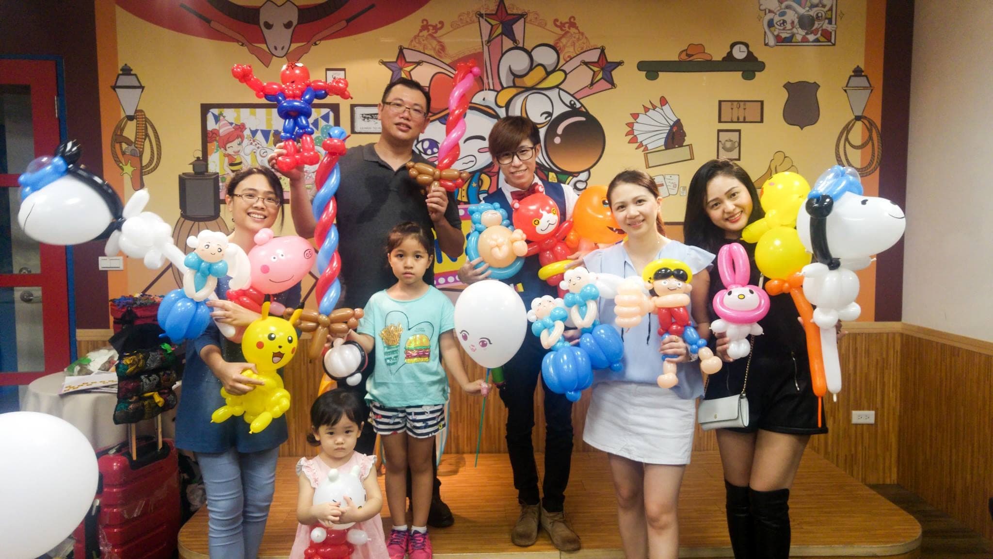 台中棒恰恰親子餐廳牛仔風彩繪牆前，大人小孩拿著蜘蛛人、皮卡丘等造型氣球合照
