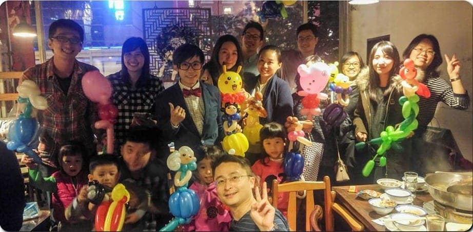 台北魯旦川鍋聖誕活動，大人小孩拿著皮卡丘、粉紅小熊等造型氣球在火鍋桌旁合照