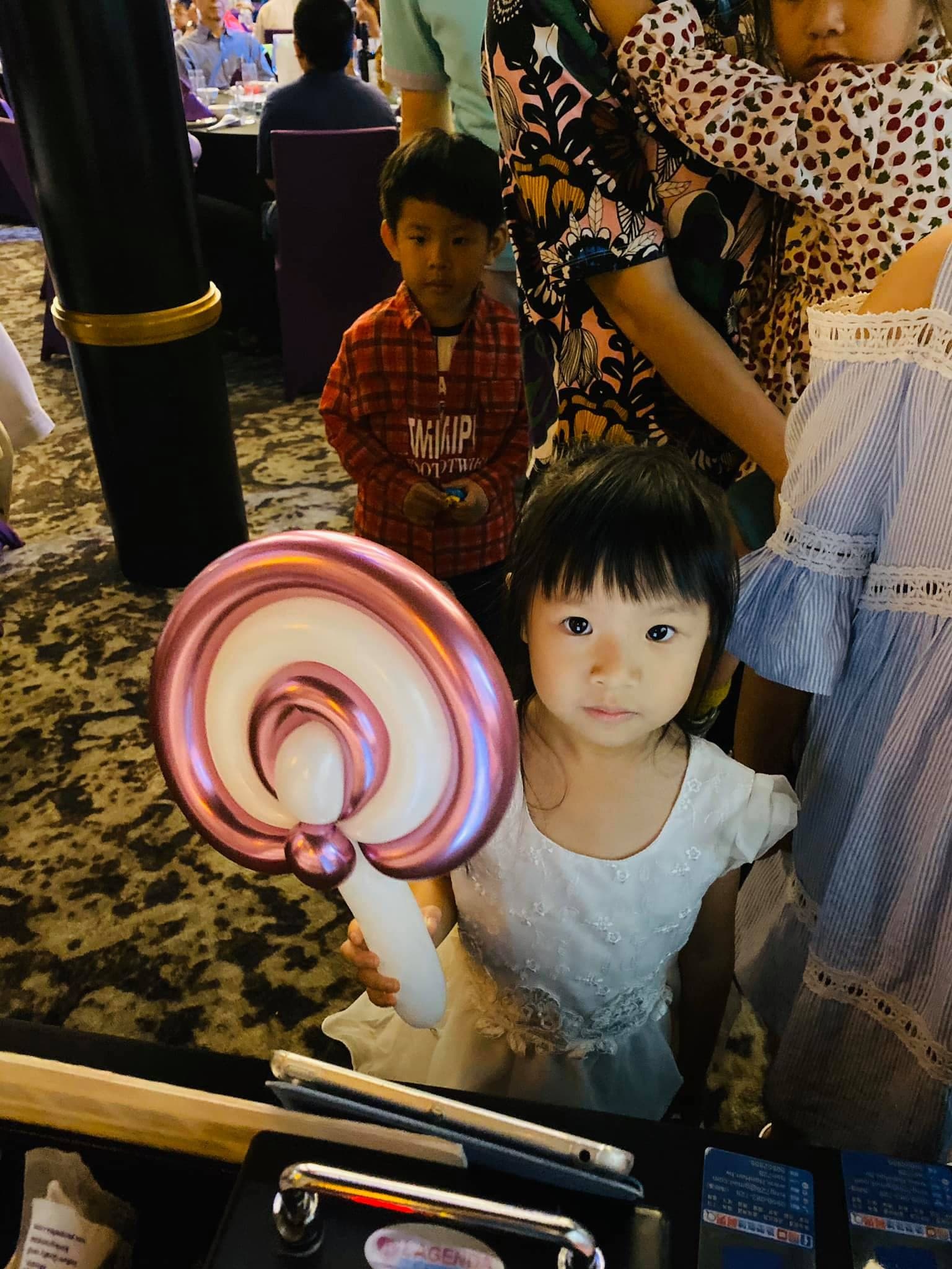 小女孩拿著金屬紫色的棒棒糖造型氣球