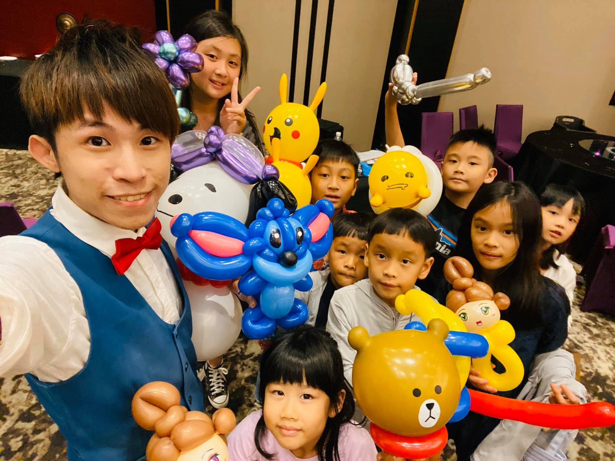 氣球達人和一群小朋友自拍，手上有皮卡丘、史迪奇、熊大造型氣球