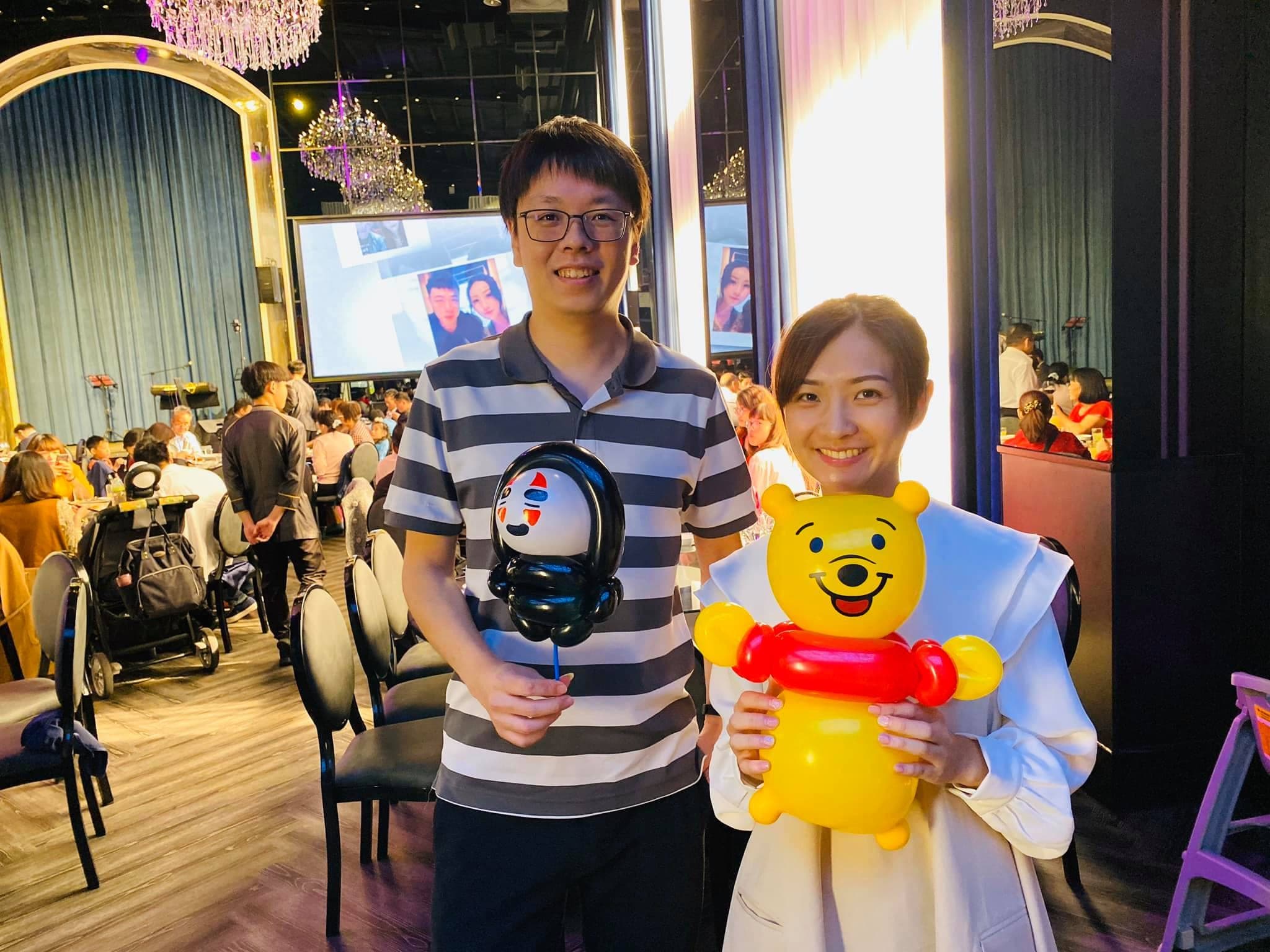 一對賓客拿著黑色面具造型與小熊維尼氣球