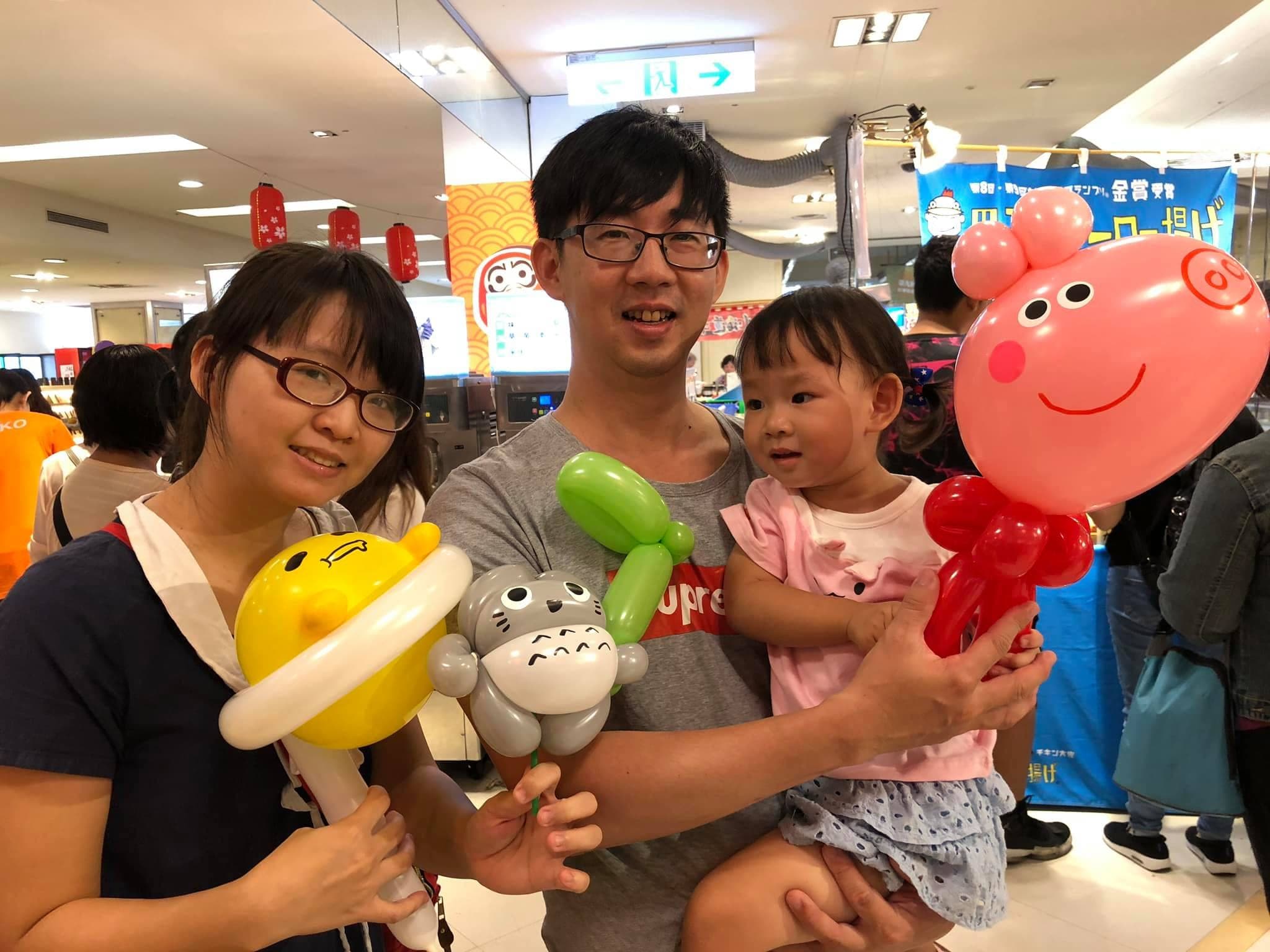 一家三口拿著龍貓、粉紅小豬與黃色造型氣球
