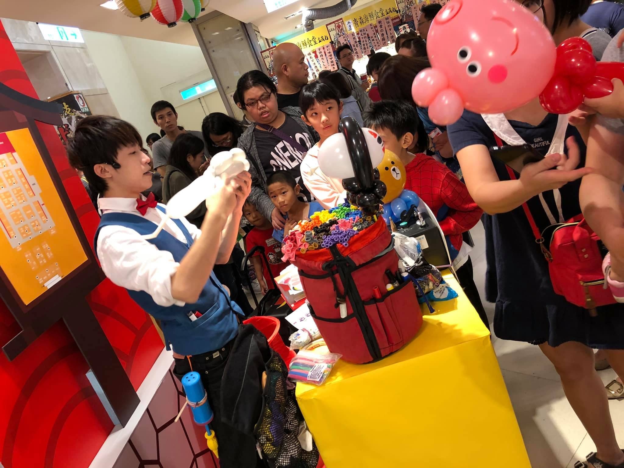 日本展攤位上，我拿著白色氣球為排隊民眾製作