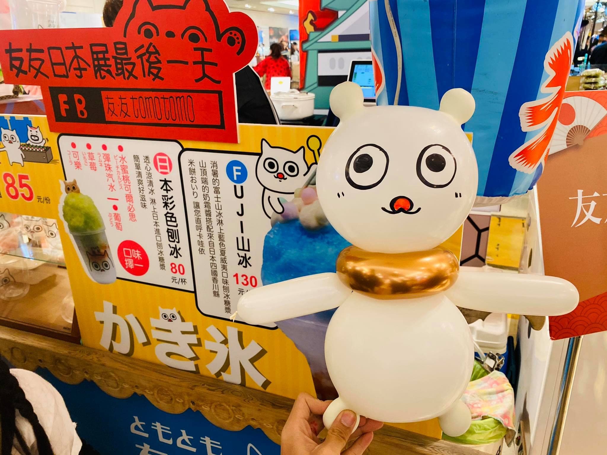 刨冰攤位前，戴金色項圈的白色小熊造型氣球