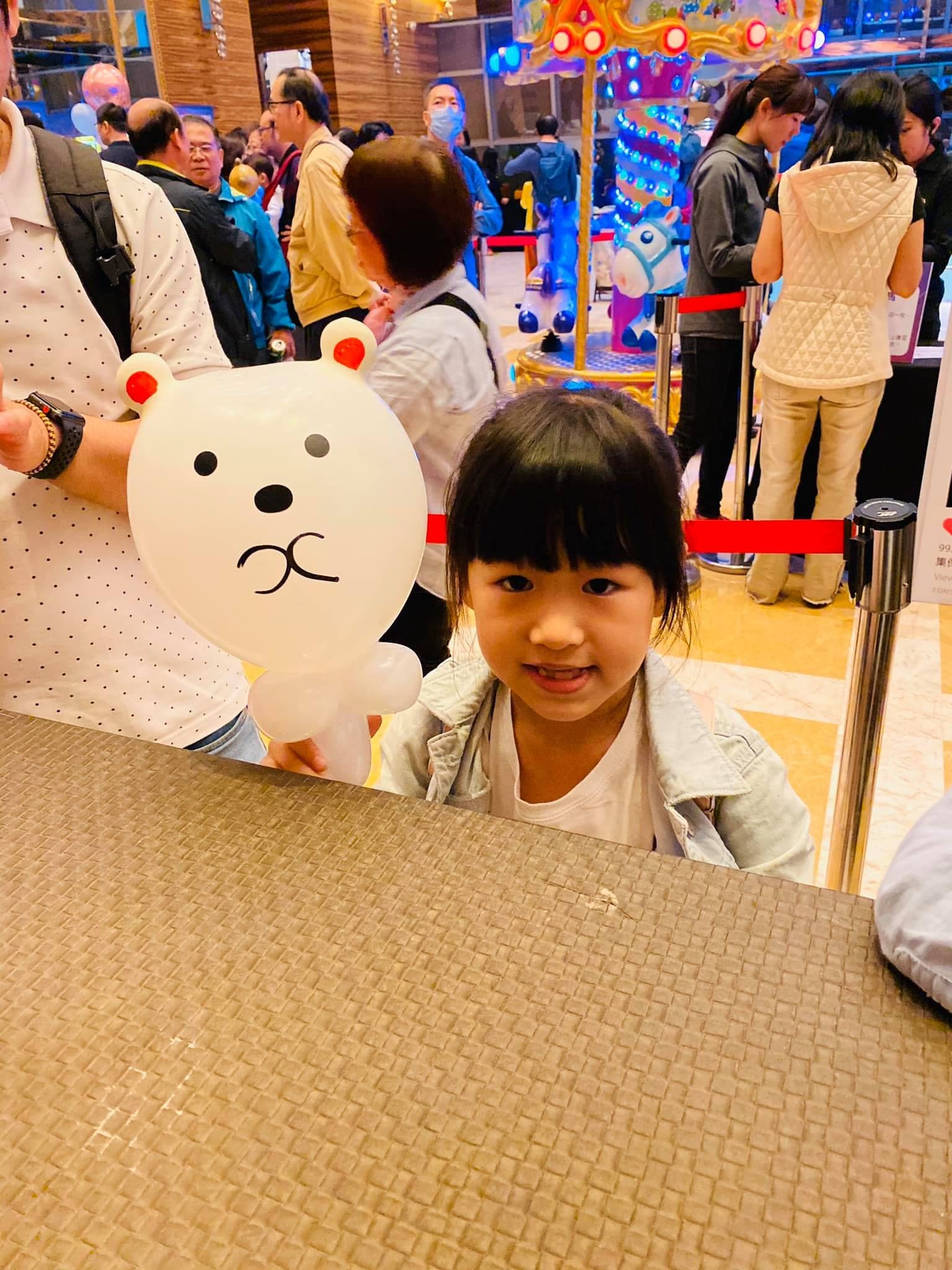 典華大廳旋轉木馬前，小女孩拿著白色小熊造型氣球