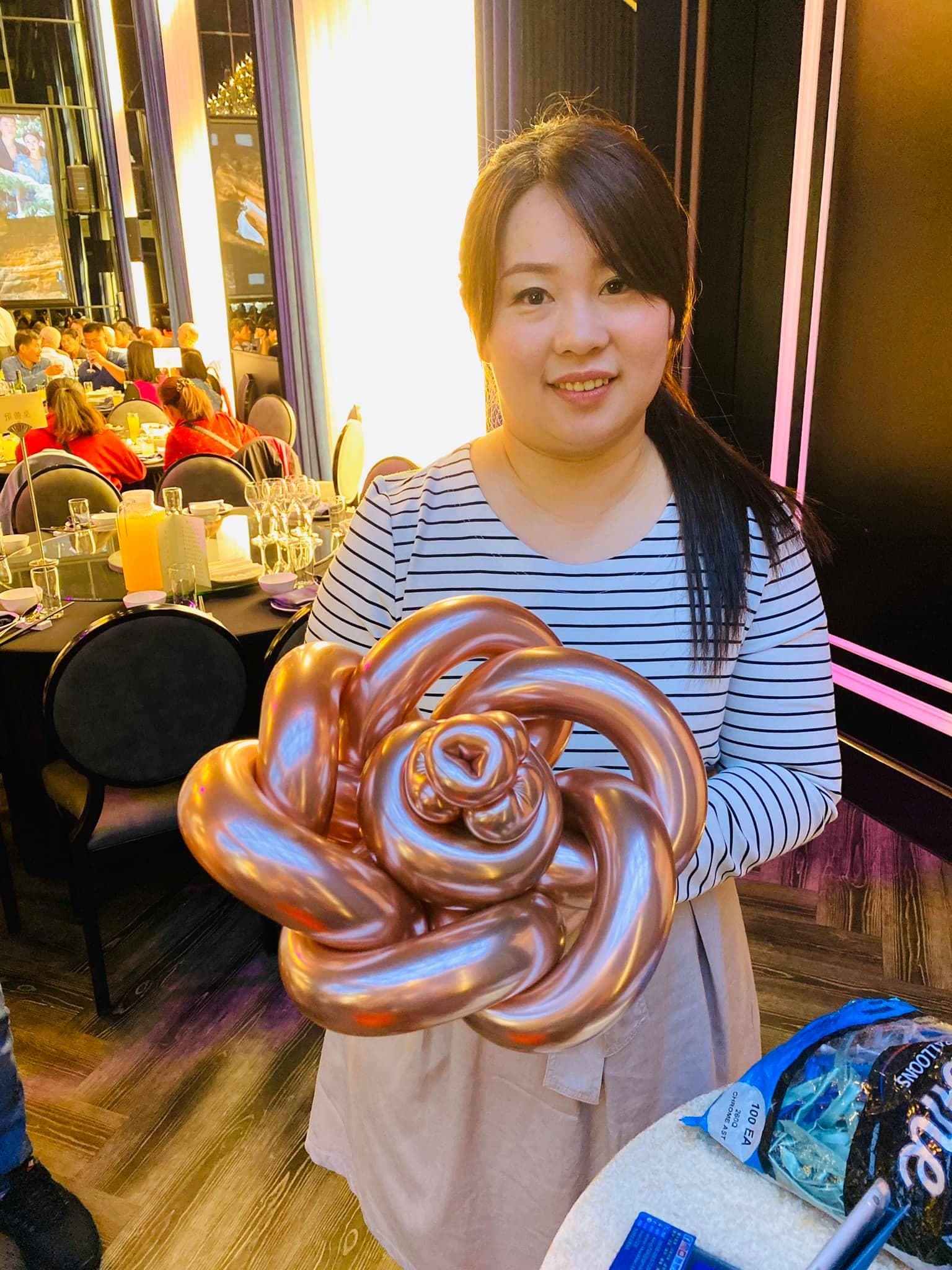穿條紋上衣的女生拿著玫瑰金色的玫瑰造型氣球