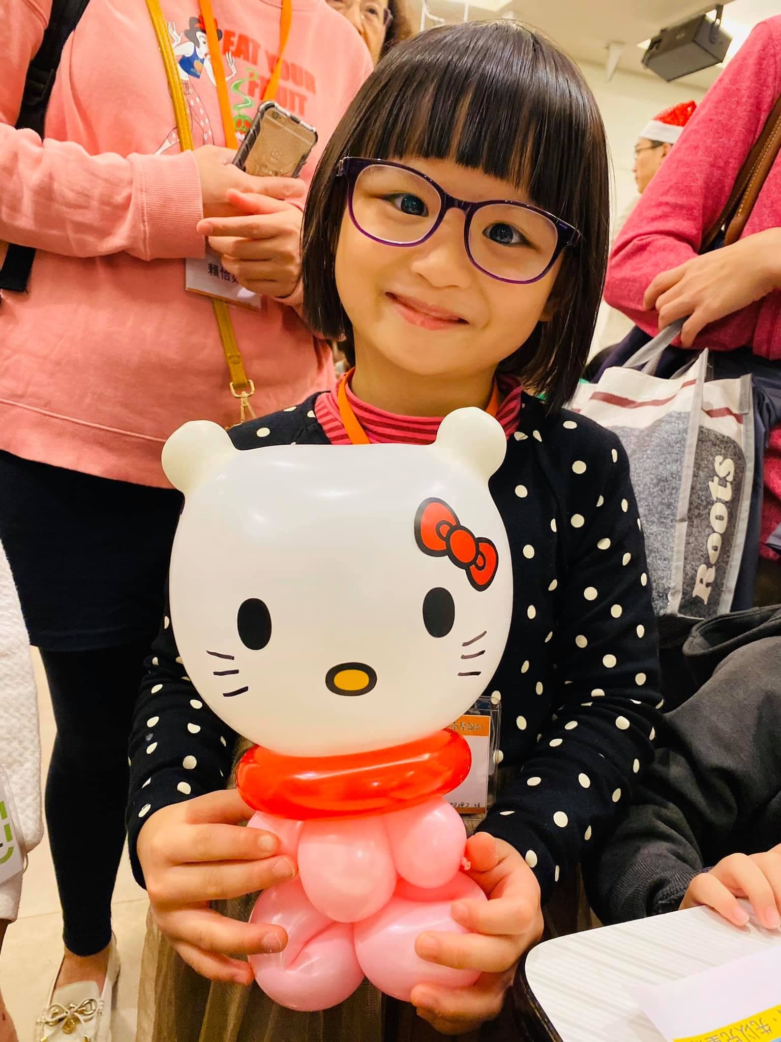 戴眼鏡的小女孩抱著 Hello Kitty 全身造型氣球