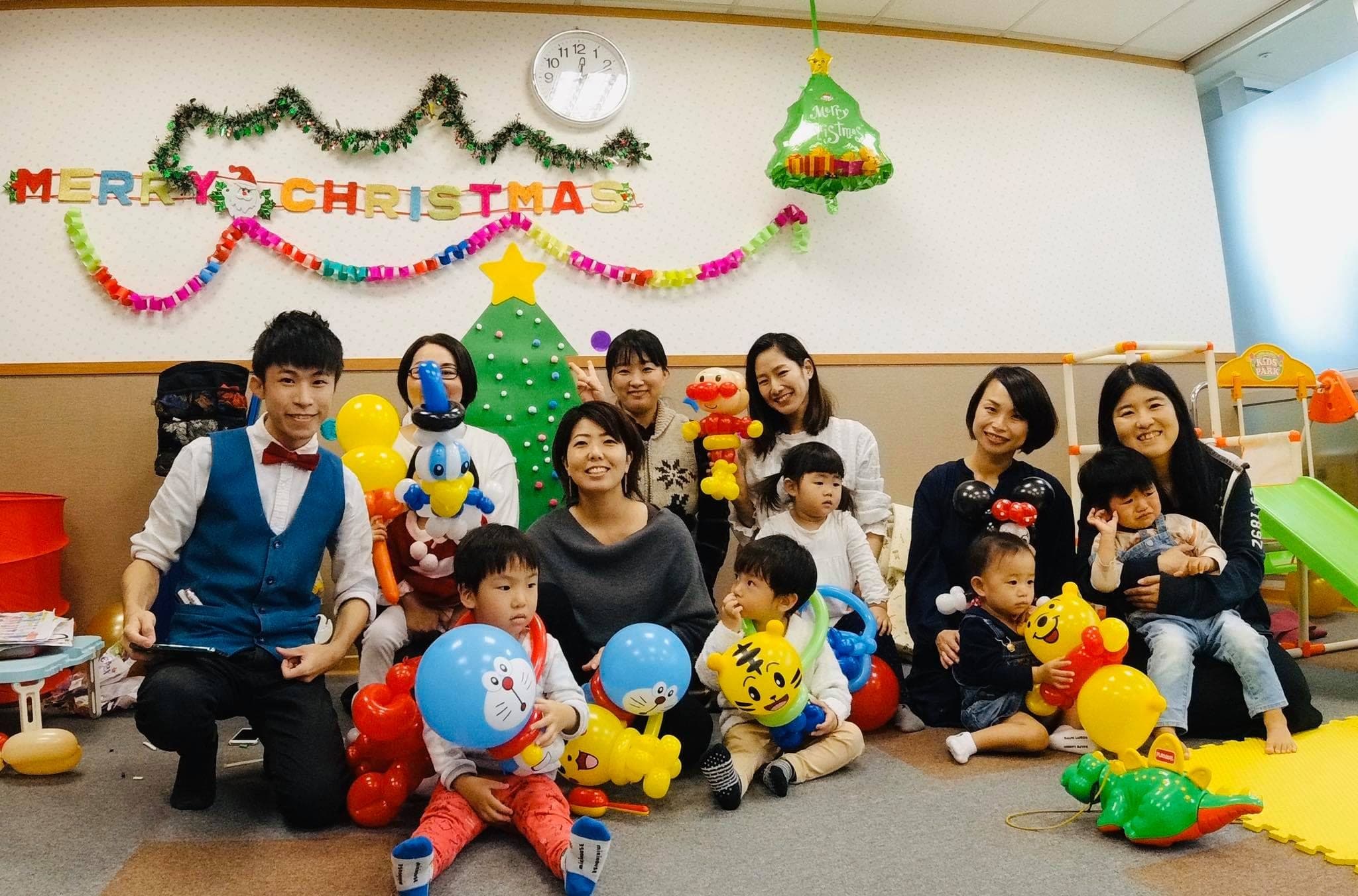 MERRY CHRISTMAS 字樣下，日本家庭的媽媽和孩子拿著氣球與我合照