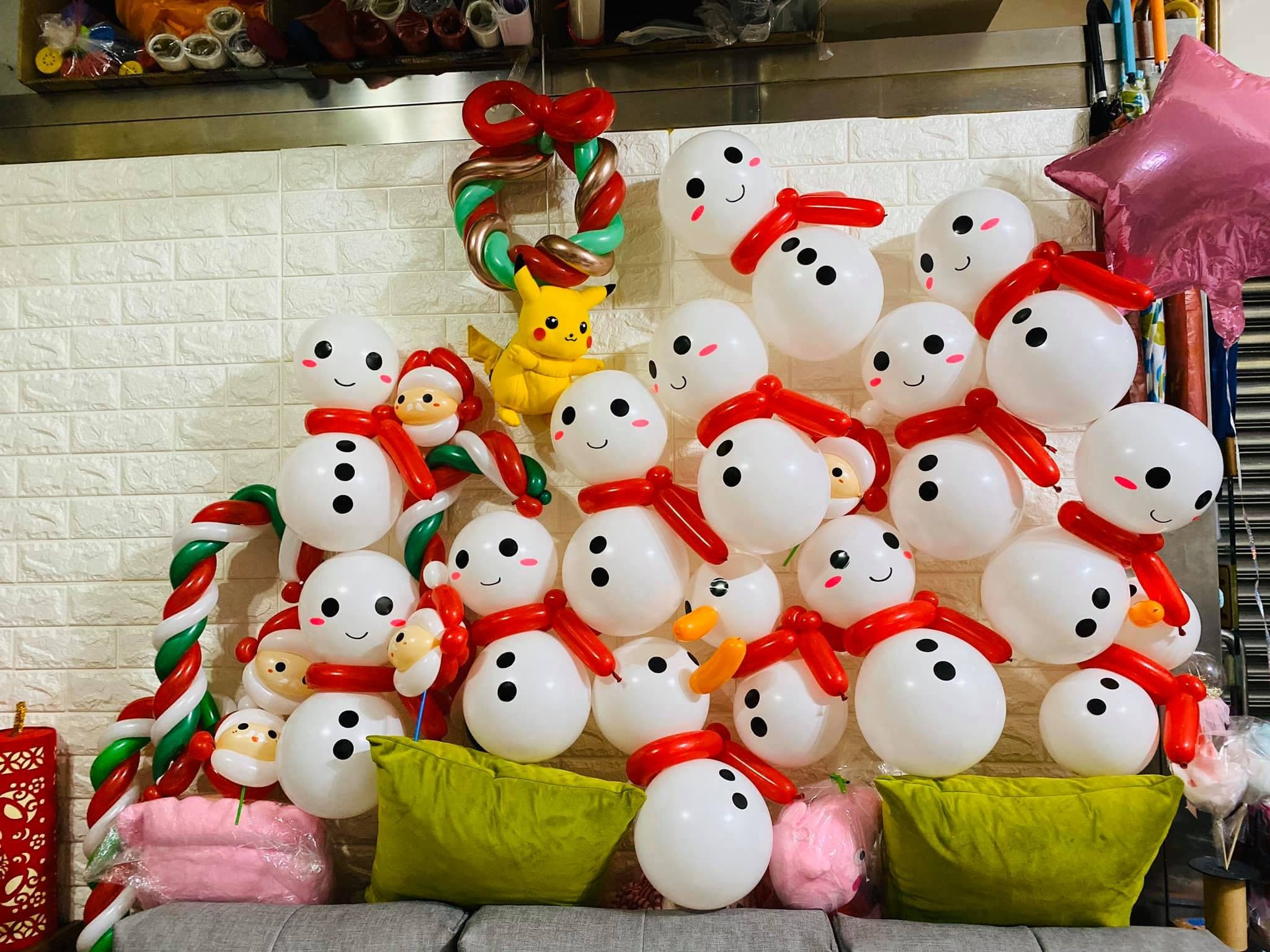 沙發上堆滿圍紅圍巾的雪人氣球，夾雜聖誕老人、皮卡丘與花圈