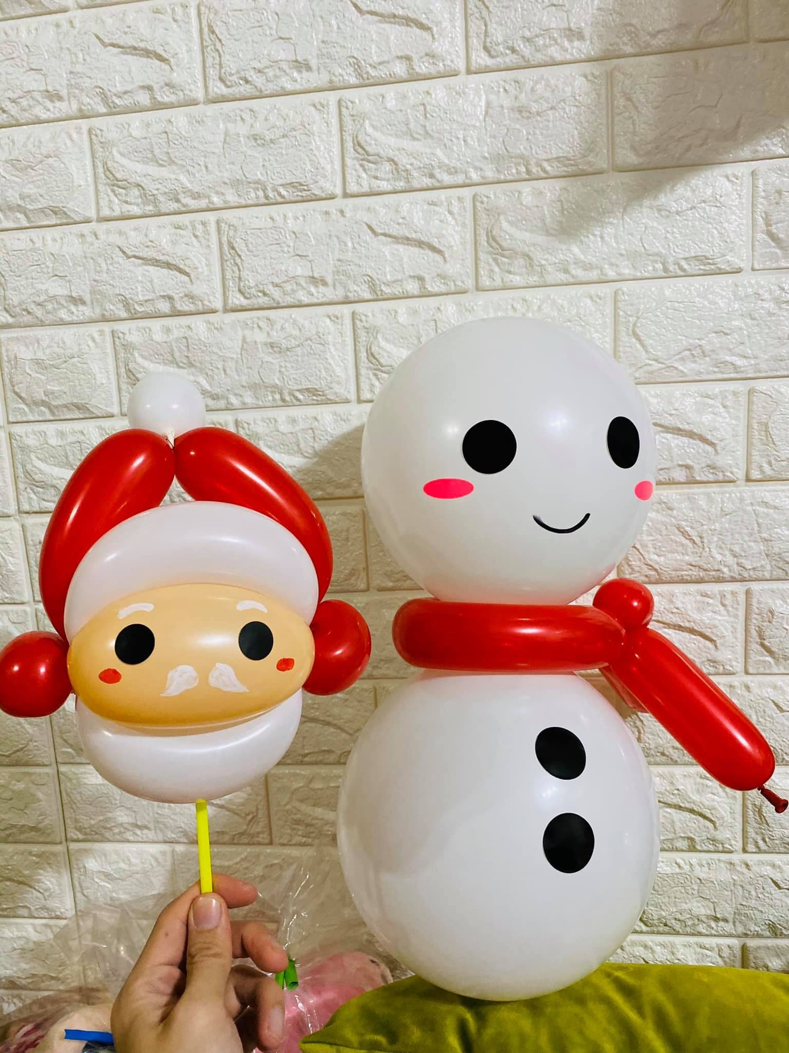 白磚牆前的聖誕老人臉手拿棒與紅圍巾雪人氣球特寫