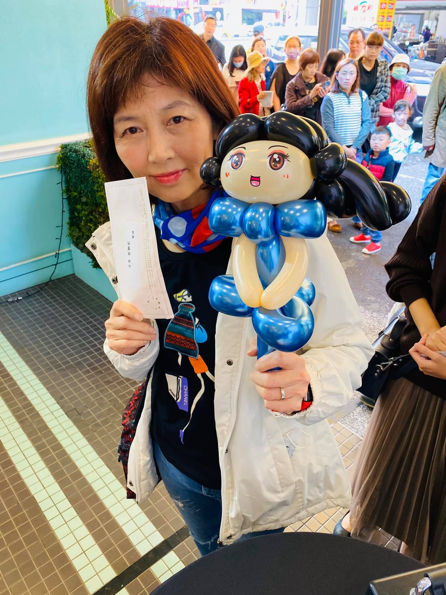 拿著號碼牌的女士舉起黑髮藍衣的白雪公主氣球