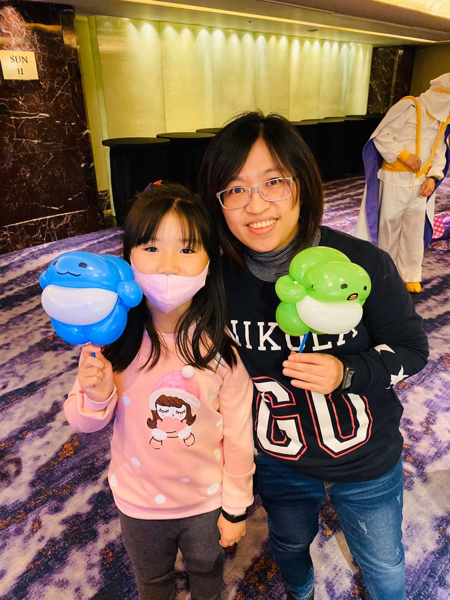 媽媽和女兒分別拿著藍色小鯨魚與綠色小烏龜氣球