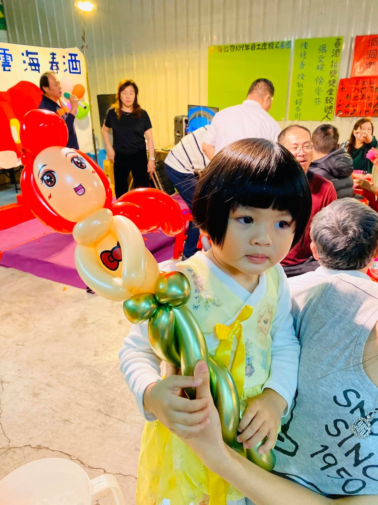 穿黃色衣服的小女孩拿著紅髮金綠尾巴的小美人魚氣球