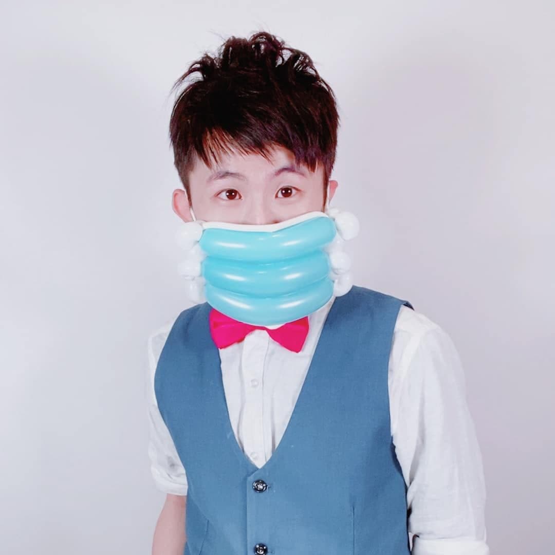 2 月作品照：我戴著淺藍色長條氣球做成的口罩，白色背景前