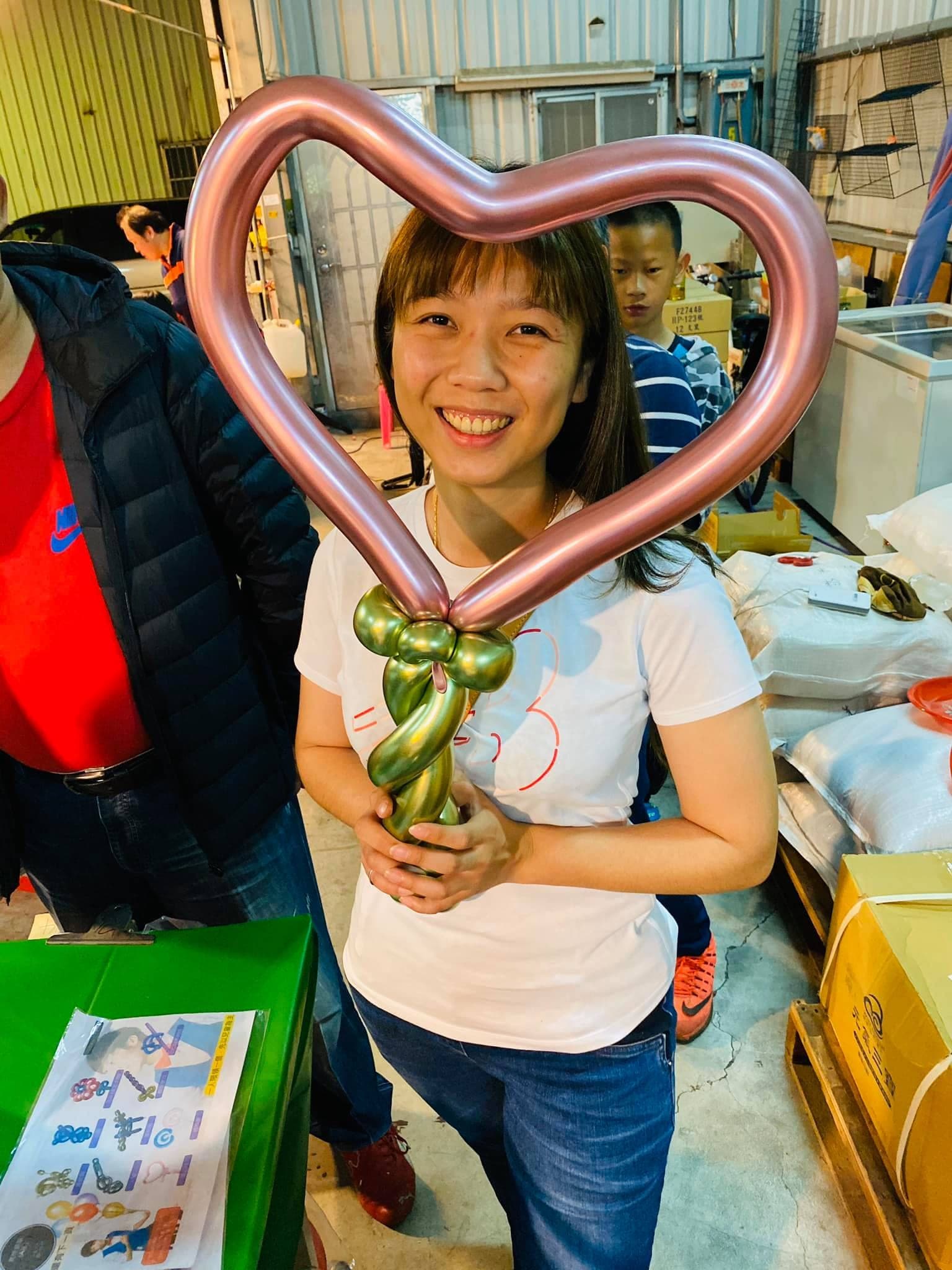 女性來賓把玫瑰金愛心手拿棒舉在臉前，握把是金屬綠扭花