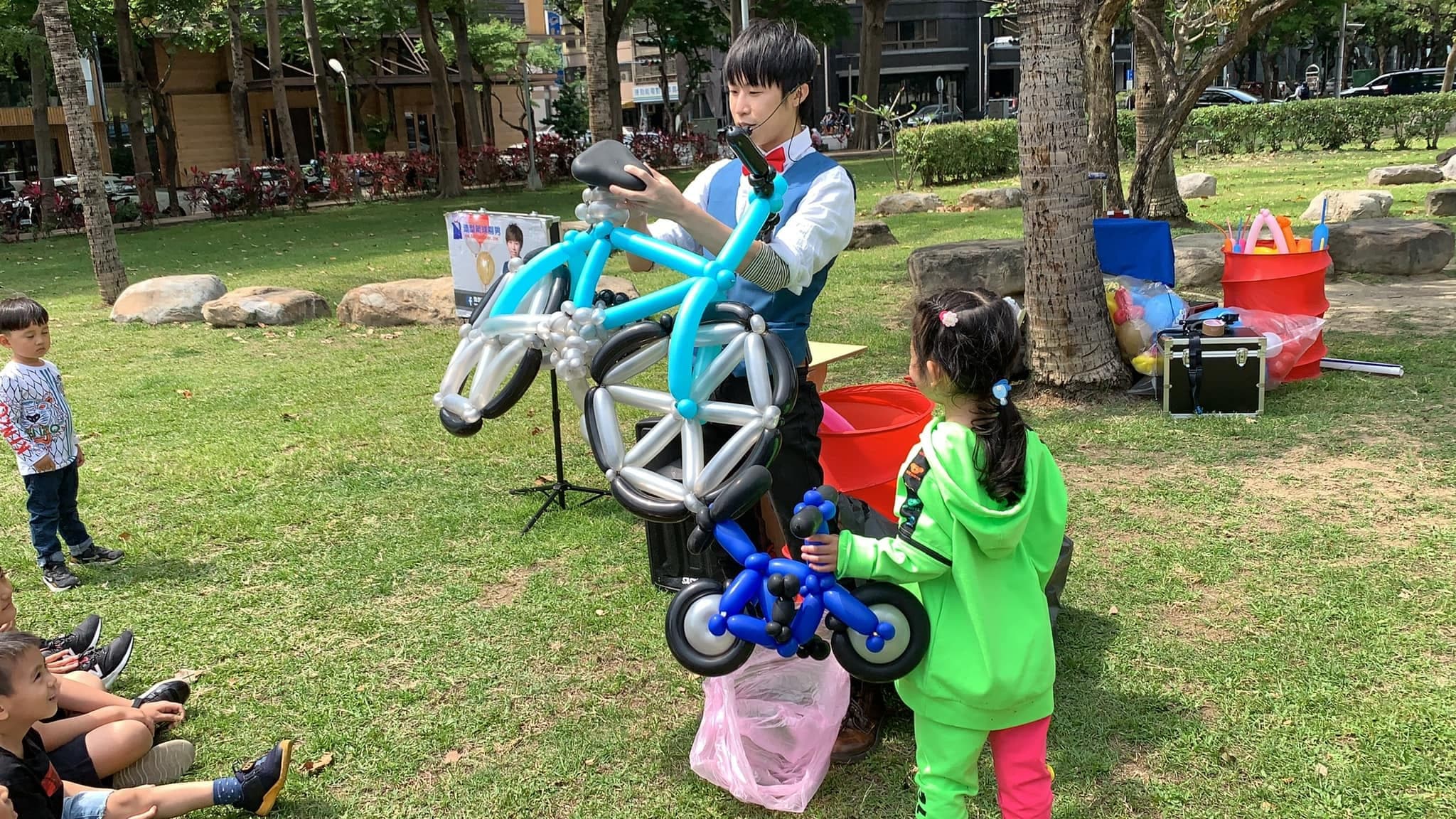 我舉起淺藍色大型腳踏車氣球，綠衣小壽星抱著藍色小腳踏車