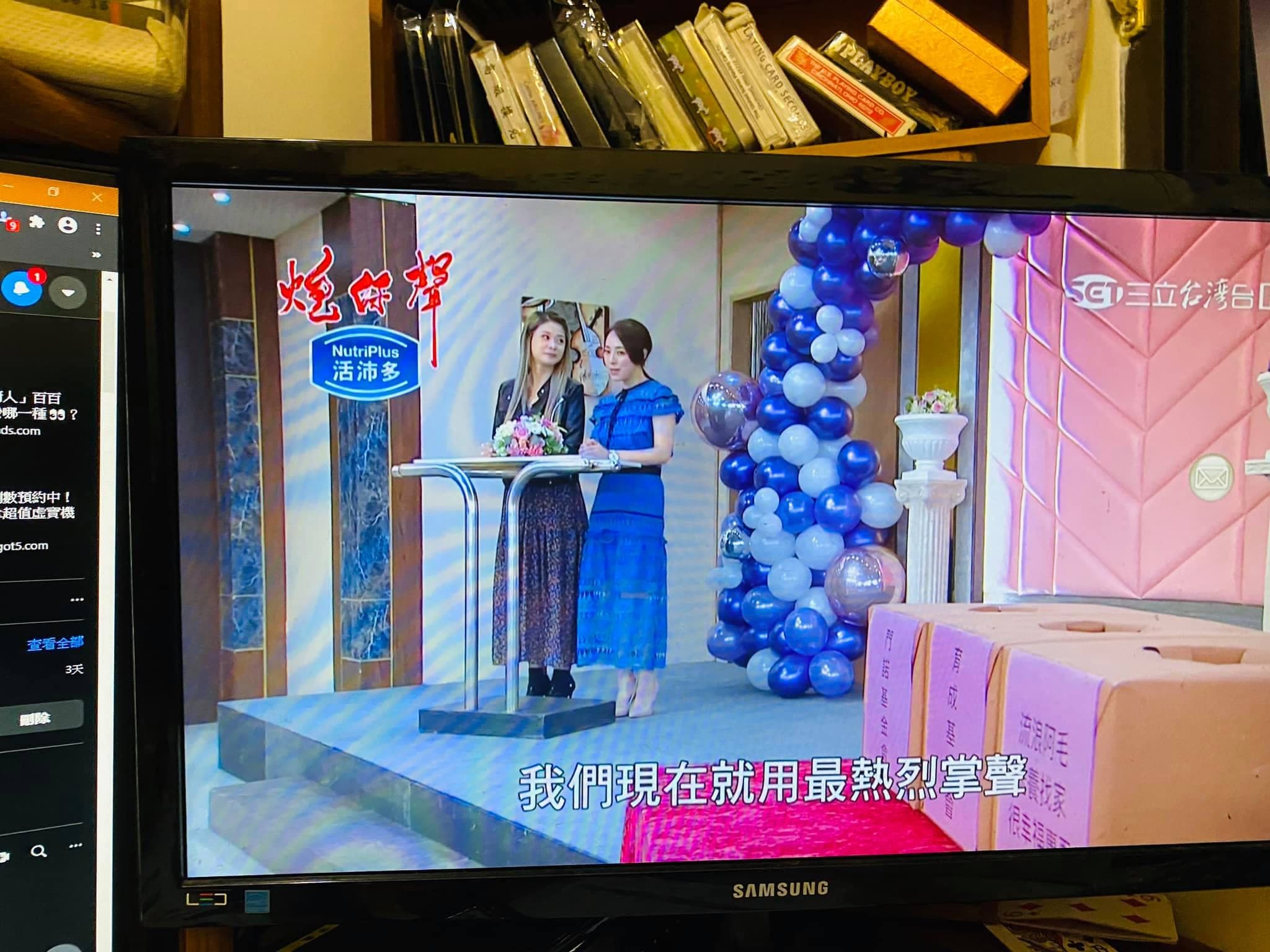 電視播出的炮仔聲片段，兩位演員站在舞台講台前，右側是藍白不規則氣球柱