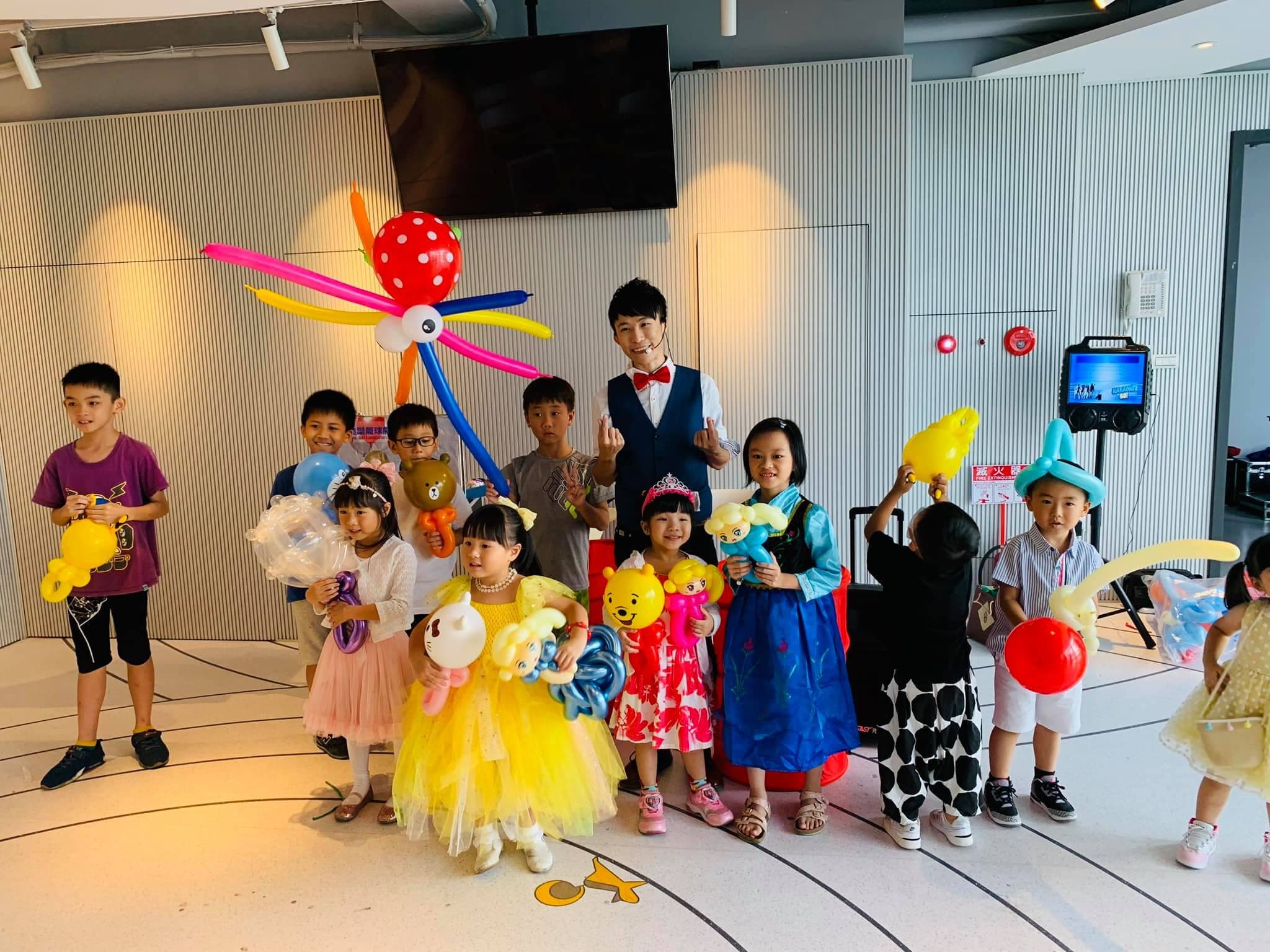 生日派對表演後大合照，小朋友拿著章魚、小熊維尼等造型氣球
