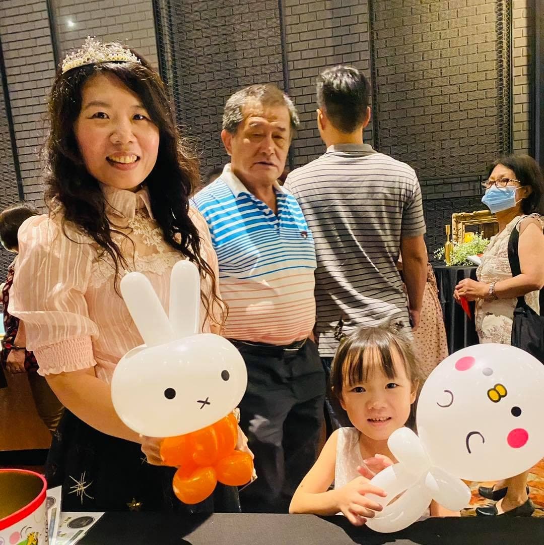 戴皇冠的女士拿米飛兔氣球，小女孩抱白色圓臉氣球