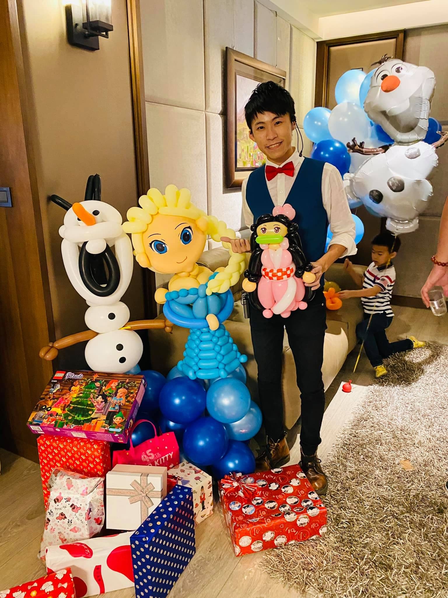 台南艾莎生日派對，大型艾莎與雪寶氣球人偶旁的柯男手拿禰豆子氣球