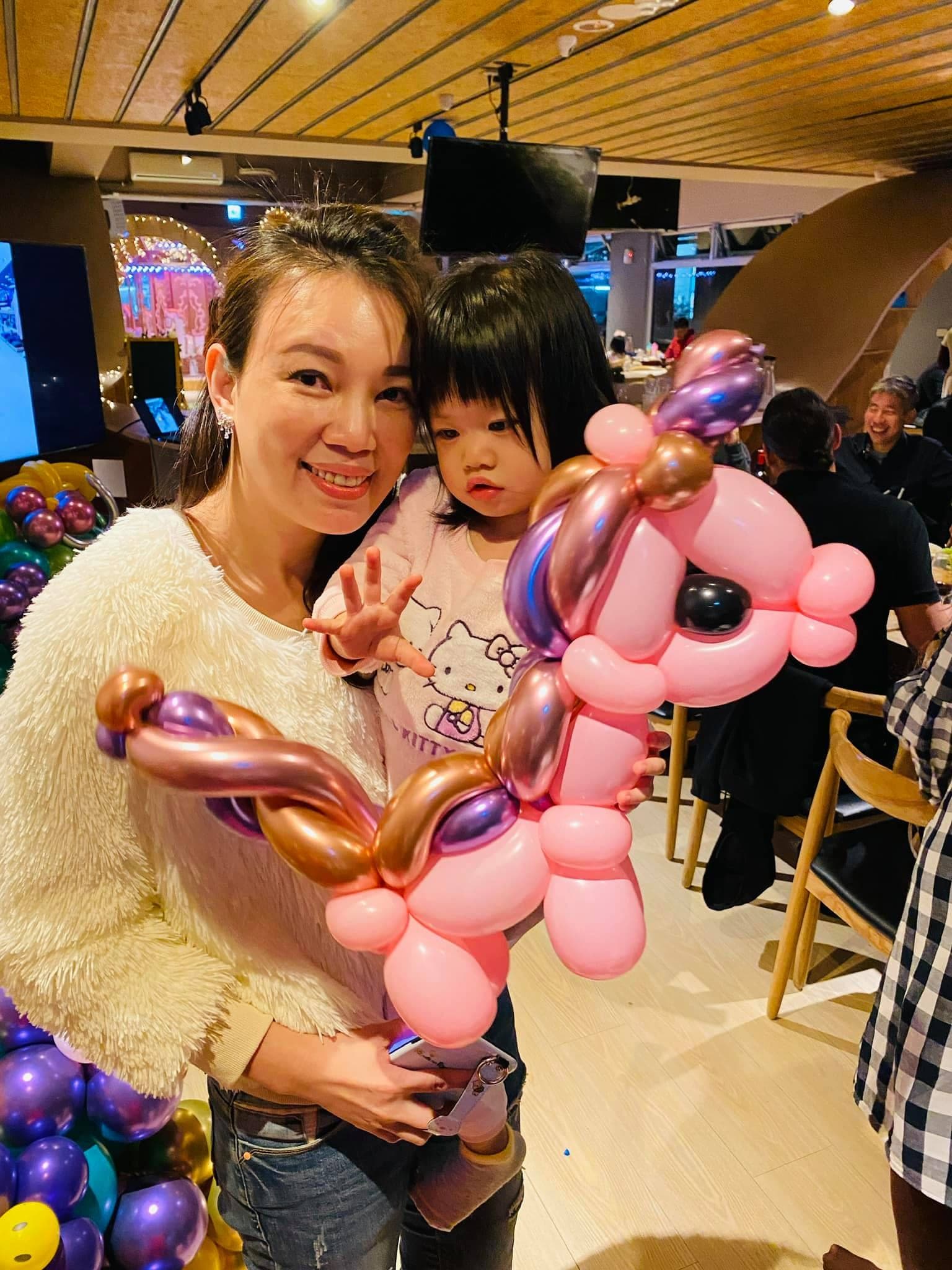媽媽和女兒拿著紫色鬃毛的粉紅小馬造型氣球