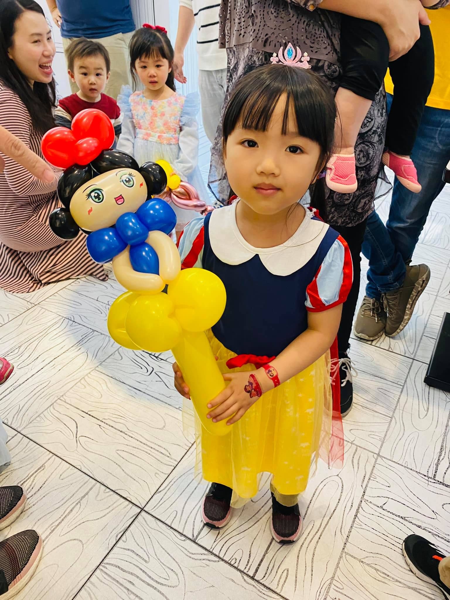 穿白雪公主服裝的女孩抱著白雪公主造型氣球