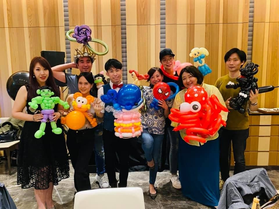 大人生日派對合照，每人拿著章魚、鯨魚蛋糕、綠色肌肉人等氣球