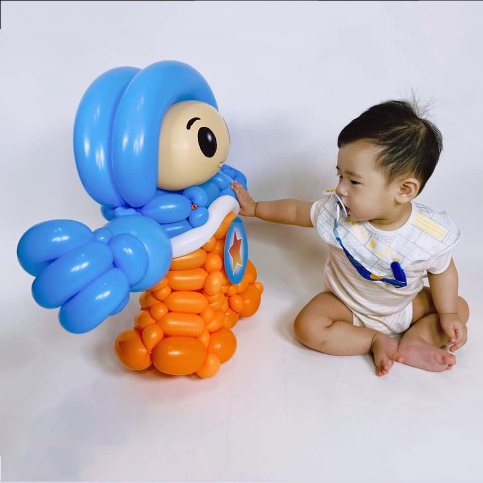 凱恩氣球人偶側面，小寶寶伸手摸胸前的紅星圓徽