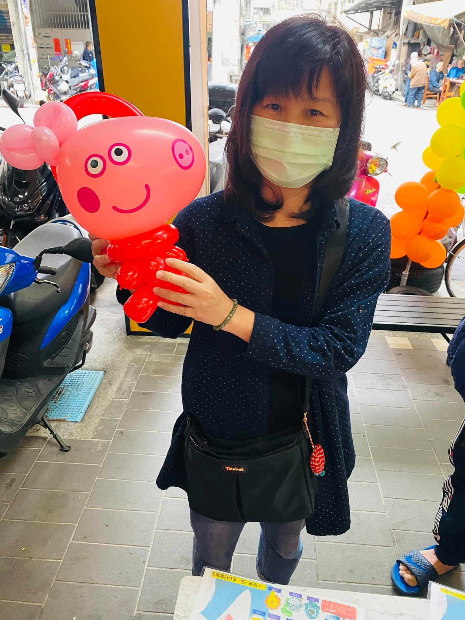 女士抱著粉紅色佩佩豬造型氣球，紅色身體