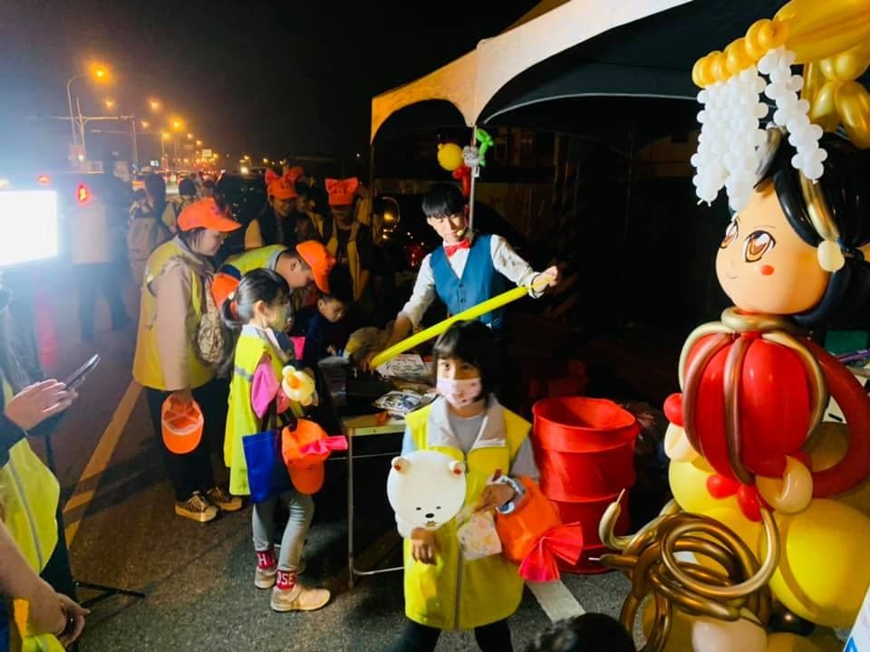 穿黃色背心的進香小朋友在夜間氣球攤位前等氣球
