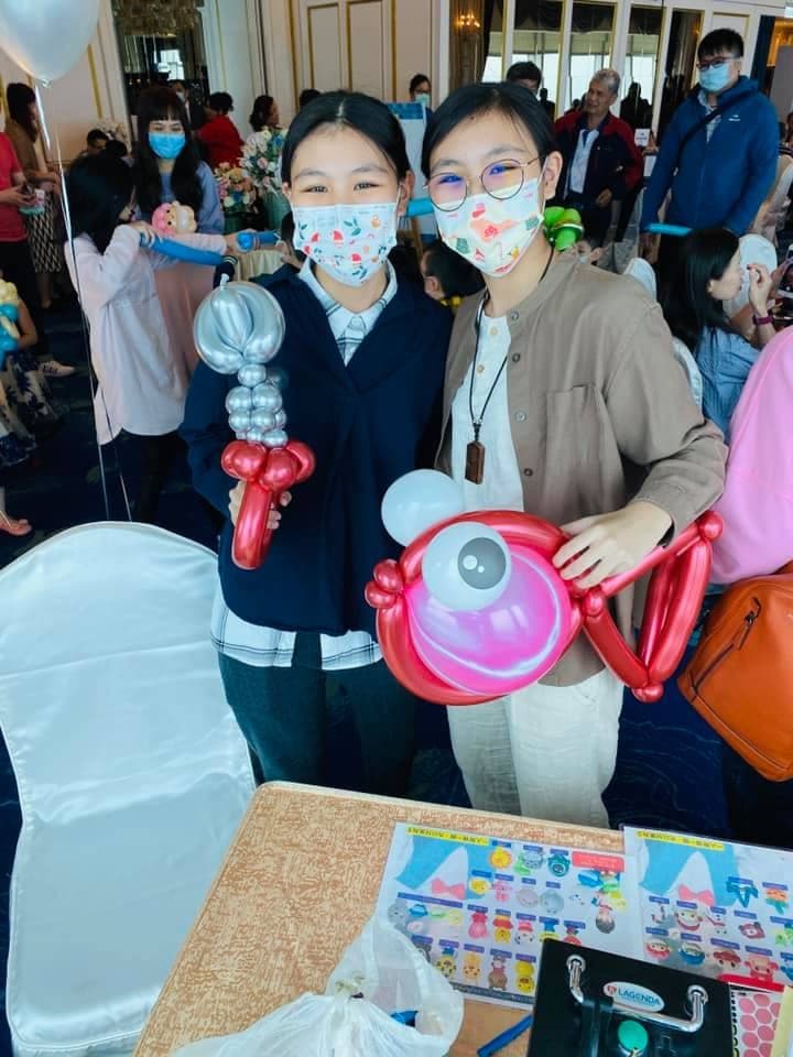 兩位賓客拿著銀色寶劍與粉紅色圓形造型氣球合照