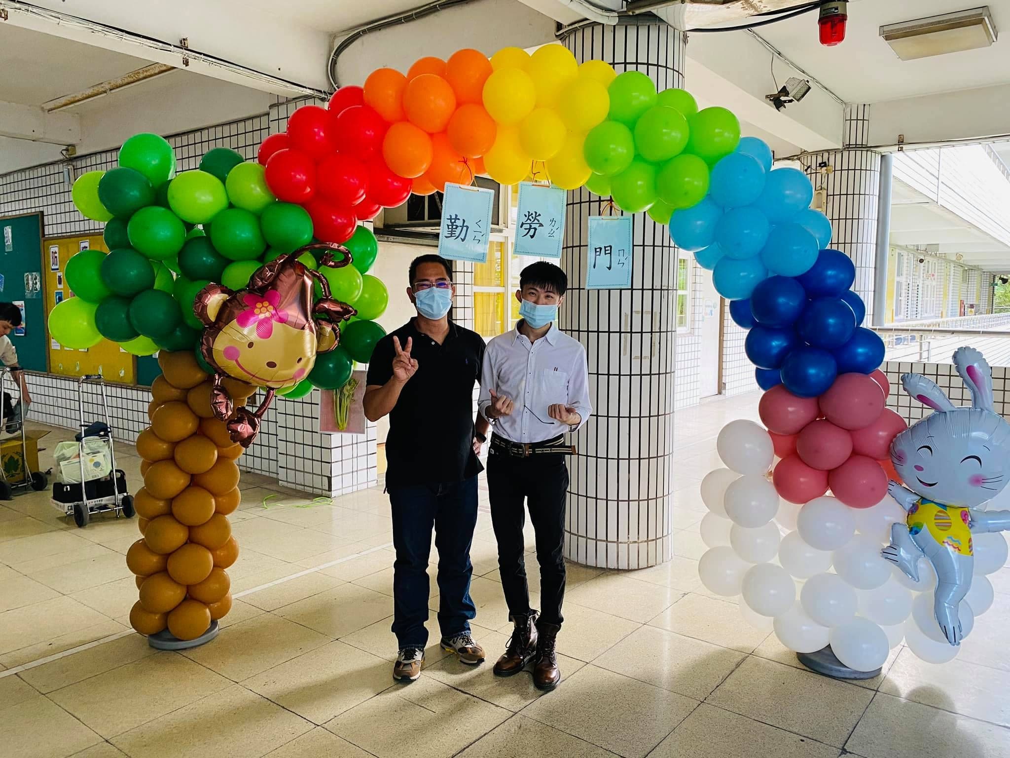 柯男與校長在彩虹樹雲朵氣球拱門下合影